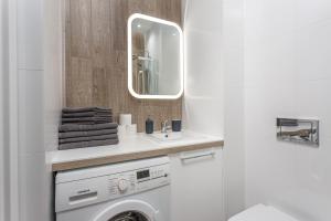 a bathroom with a washing machine and a mirror at Chill Apartments Warsaw Airport in Warsaw