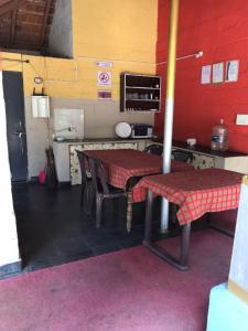 kuchnia z dwoma stołami i czerwoną ścianą w obiekcie Silver Shadow Homestay w mieście Chikmagalur