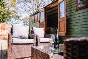 a patio with wicker chairs and a table with a bottle of wine at Snowdrop Lodge, Walcot Hall Estate in Alkborough