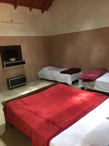 Pokój z dwoma łóżkami z czerwonymi kocami na nich w obiekcie Silver Shadow Homestay w mieście Chikmagalur