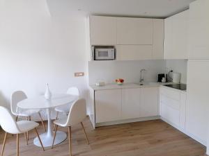 a white kitchen with a white table and chairs at La conchiglia, air conditioning, parking in Rapallo
