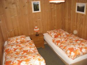 2 letti in una camera con pareti in legno di Chalet Suveran 1 a Arosa
