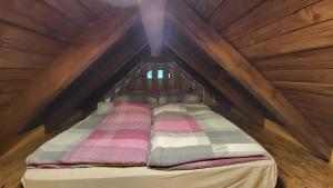 a bed in the attic of a wooden cabin at Glamping Fikfak in Bled