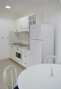 a kitchen with white cabinets and a white refrigerator at Eco Village Buljarica in Budva