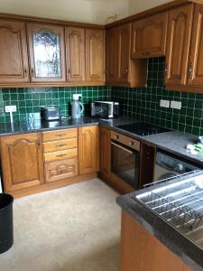 a kitchen with wooden cabinets and green tile at 5/6 Bed House Barnsley Centre in Barnsley