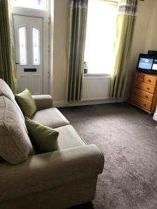 a living room with a couch and a television at 5/6 Bed House Barnsley Centre in Barnsley