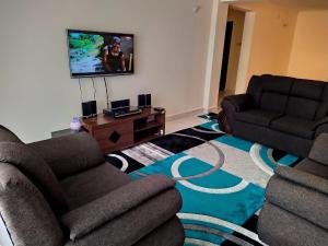 a living room with two couches and a flat screen tv at Amohela Serviced Apartments - Kisumu in Mamboleo