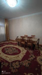 ein Esszimmer mit einem Tisch, Stühlen und einem Teppich in der Unterkunft Umid Hostel in Buxoro