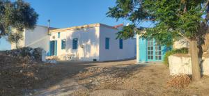 una casa blanca con ventanas azules y un árbol en Αρχοντικό ΑΤΤΙΚ - ATTIK MANSION, en Livadi