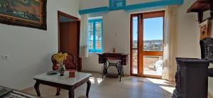 a living room with a table and a window at Αρχοντικό ΑΤΤΙΚ - ATTIK MANSION in Livadi