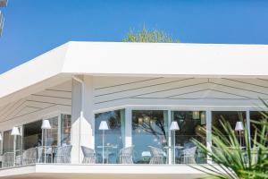 a white building with chairs and tables on it at Hotel San Giorgio in Caorle
