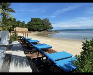 Nam Jai Beach - Sunset في بانبانغْ بو: صف من الطاولات والكراسي الزرقاء على الشاطئ