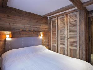 una camera da letto con pareti in legno e un letto bianco di Chalet cosy proche des pistes avec sauna et cheminée - Courchevel 1850 - FR-1-564-25 a Courchevel