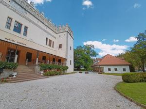 a large white building with a driveway in front of it at Kaštieľ Fričovce in Fričovce