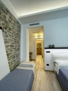 a bedroom with two beds and a stone wall at Civico29 Rooms & Breakfast in Como