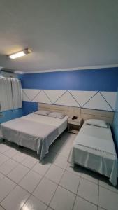 a bedroom with two beds and a blue wall at Hotel Porthal da Ilha- Paulo Afonso-Ba in Paulo Afonso