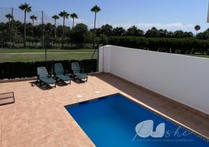 a swimming pool with lounge chairs and a fence at PUSHE Village Playa Granada Beach & Golf 3 in Motril