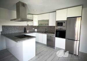 a kitchen with white cabinets and stainless steel appliances at PUSHE Village Playa Granada Beach & Golf 3 in Motril