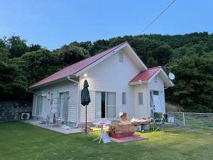 ein weißes Haus mit einem Tisch und einem Regenschirm in der Unterkunft Holiday Villa 旅生 in Tonosho