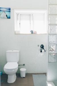 Un baño blanco con inodoro y ventana. en Ocean Guesthouse Peniche, en Peniche