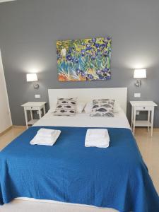 a bedroom with a blue bed with two pillows and a painting at Mini appartamento Aria in OstuniCrispiHouse in Ostuni +17 photos