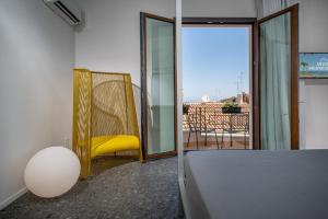 a bedroom with a yellow chair and a balcony at BED 10.5 - DESIGN SUITE in Castellammare del Golfo
