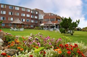 Portobello Suites Hotel في لا بالوما: مبنى امامه حديقة فيها ورد