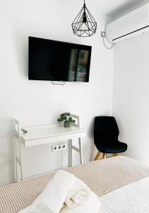 Hostal Las Palmas في كاربونيراس: غرفة نوم مع مكتب وتلفزيون على الحائط