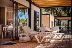 un patio con mesas y sillas blancas en una terraza en Arena Stoja Camping Homes en Pula