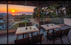 two tables and chairs on a balcony with the sunset at LUNAR in Skala Rachoniou