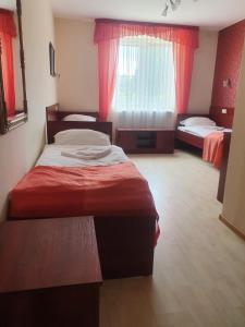 um quarto de hotel com duas camas e cortinas vermelhas em Gościniec Zodiac em Rzuchów