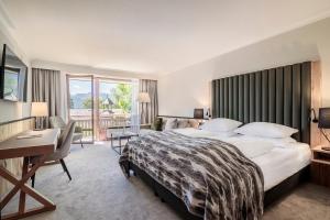 ein Hotelzimmer mit einem großen Bett und einem Schreibtisch in der Unterkunft Alpenhof Murnau in Murnau am Staffelsee