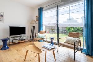 a living room with a large window and a tv at Belle maison familiale et contemporaine avec piscine in Nantes