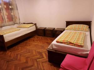 two beds in a room with wooden floors at Farkas Szálló in Báránd