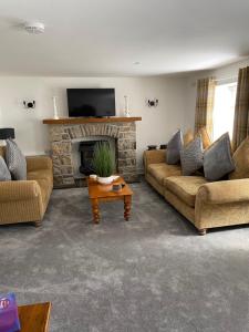 sala de estar con 2 sofás y chimenea en The Cottage, en Ystradgynlais
