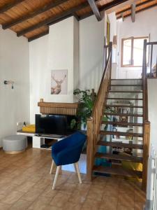 a living room with a staircase and a blue chair at L'Azilienne, jolie maison à 2 pas du village - L'Azilienne, pretty house 2 steps from village in Le Mas-dʼAzil