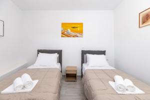 two beds in a room with white walls at Villa Ostrich in Fira
