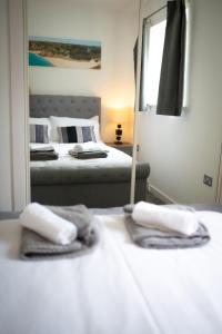 ニューキーにあるSeaview, Luxury apartment, 2 min walk to both Porth and Whipisderry beachesの鏡の前にベッド2台が備わるベッドルーム1室