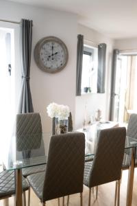 a dining room with a glass table and a clock on the wall at Sea, Stay and Relax Away - Stunning, Modern, Home from Home in Newquay +51 photos