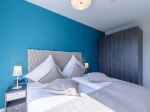 um quarto azul com uma cama grande e almofadas brancas em Boddenflair in der Seefahrtschule em Wustrow