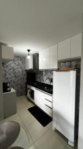 a kitchen with white cabinets and a white refrigerator at Residencial Havaí in João Pessoa