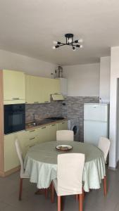una cucina con tavolo, sedie e frigorifero di Appartamento al Mare con due Terrazze a Punta Marina