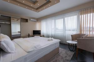 een slaapkamer met een groot wit bed en een stoel bij Hotel & Resort Bon Bon in Skopje