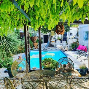 un patio con mesa, sillas y piscina en Appartement dans maison d'artiste en Lunel