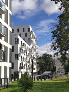 ein hohes weißes Apartmenthaus mit einem Rasenplatz in der Unterkunft Brand New and Modern 1BDR Apartment in Vilnius
