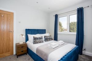 a bedroom with a bed with blue curtains and a window at The Carlton by Sorted Stay in Southend-on-Sea