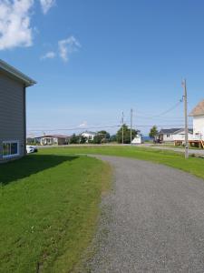 eine Schotterstraße neben einem Grasfeld in der Unterkunft Gîte du 149 route de la Mer in Sainte-Flavie