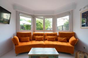 an orange couch in a living room with windows at NEW Apartment & Terrace. Steps to Ondarreta Beach in Añorga-Lugariz