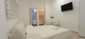 a white bedroom with a bed and a tv at Amato Luxury Apartments in Marsala