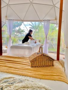 a woman sitting on a bed in a tent at Orange Glamping in Quimbaya